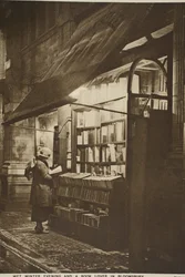 Examinando un libro fuera de una librería de segunda mano en una noche de invierno lluviosa, Bloomsbury